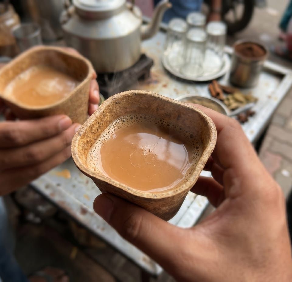 Hands holding an Aura Farmers biodegradable cup of steaming chai