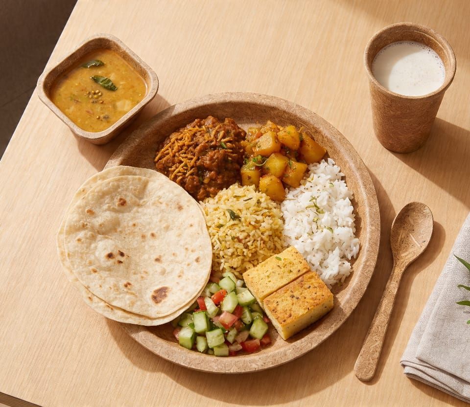 Full South Indian thali served on an Aura Farmers biodegradable plate — dal, rice, curries and chutneys